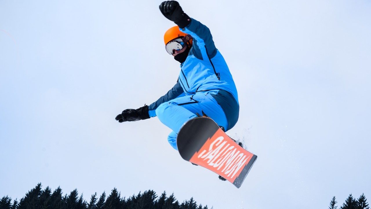 スノーボードでジャンプしている男性の画像